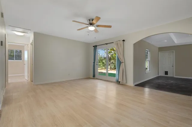 a view of an empty room with window and wooden floor