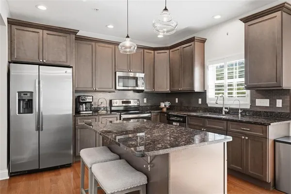 a kitchen with stainless steel appliances granite countertop a sink refrigerator and cabinets