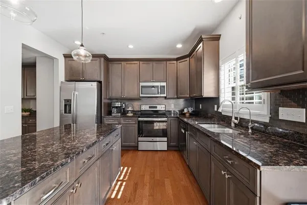 a kitchen with stainless steel appliances granite countertop a stove top oven a dining table and chairs with wooden floor