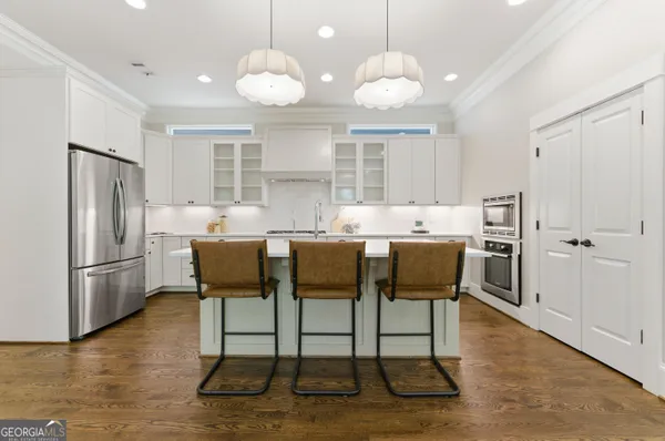 a kitchen with stainless steel appliances kitchen island granite countertop a table chairs and a refrigerator
