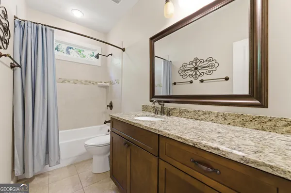 a bathroom with a granite countertop sink a toilet and shower
