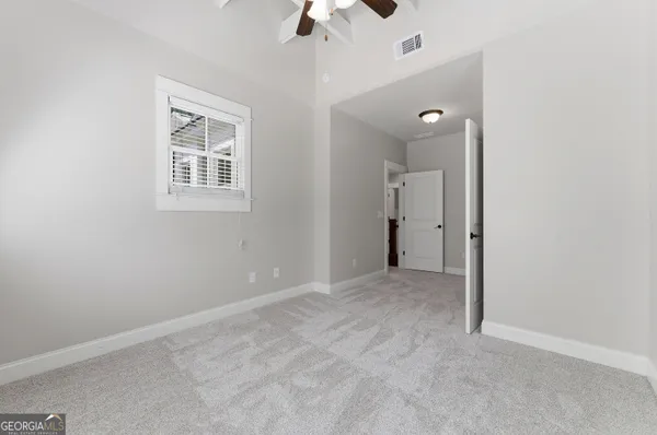 an empty room with a chandelier fan and windows