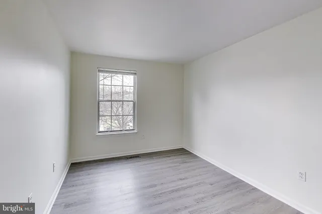 an empty room with wooden floor and window