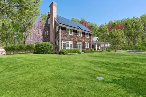 a front view of a house with garden and trees