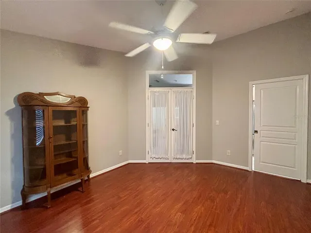 an empty room with wooden floor closet and windows
