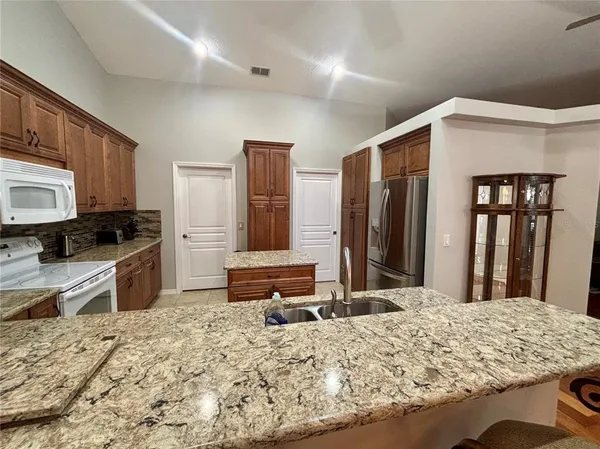 a kitchen with kitchen island granite countertop a refrigerator and a stove top oven