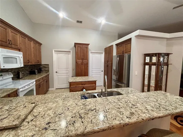 a kitchen with kitchen island granite countertop a refrigerator and a stove top oven