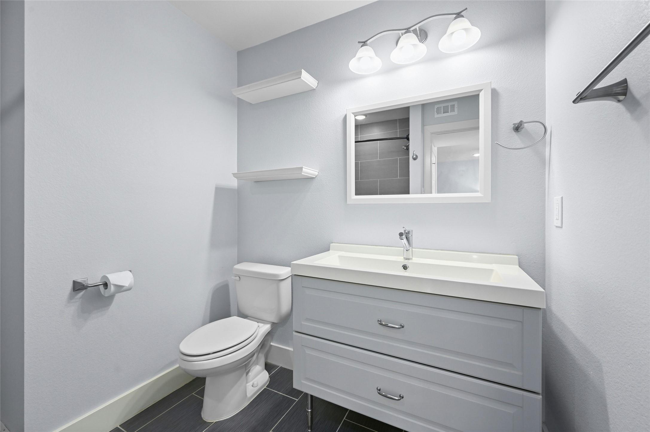 909 Reinli Street, Unit 228 Austin, TX 78751 - Photo 16 of 27 a bathroom with a toilet a sink and mirror