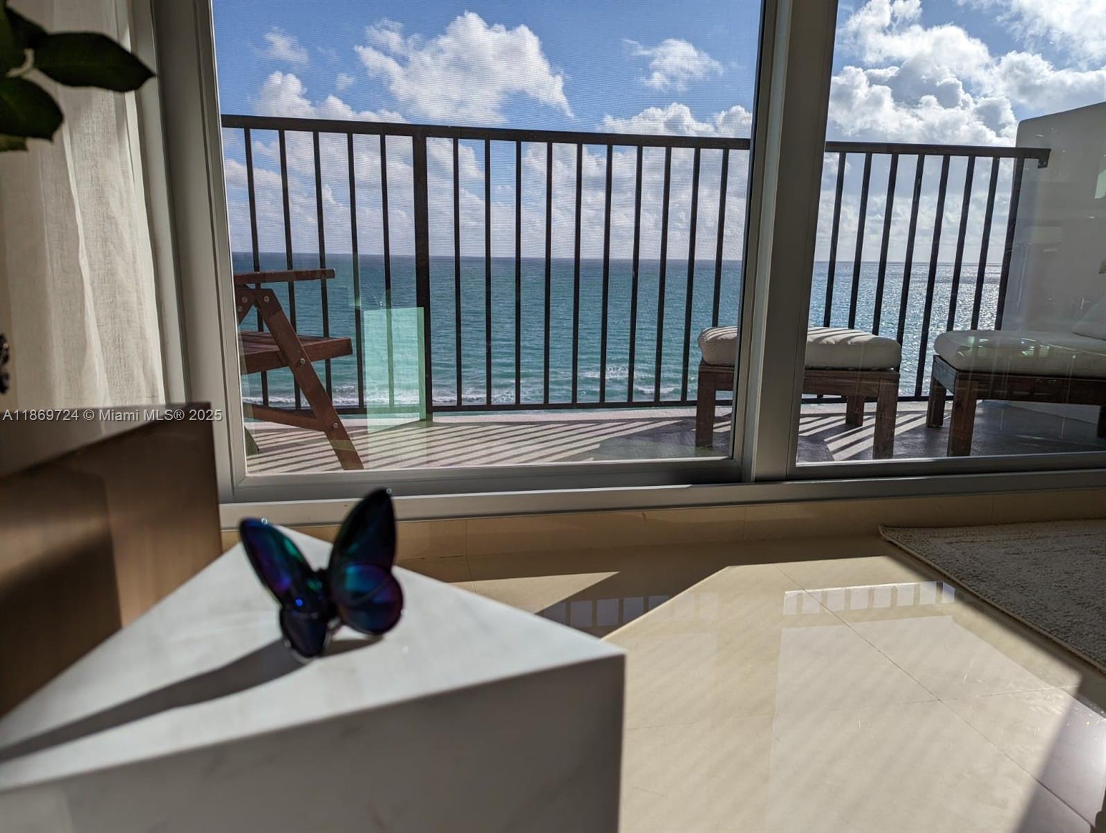 9273 Collins Avenue, Unit 1004 Surfside, FL 33154 - Photo 1 of 27 a living room with a bed and a large window