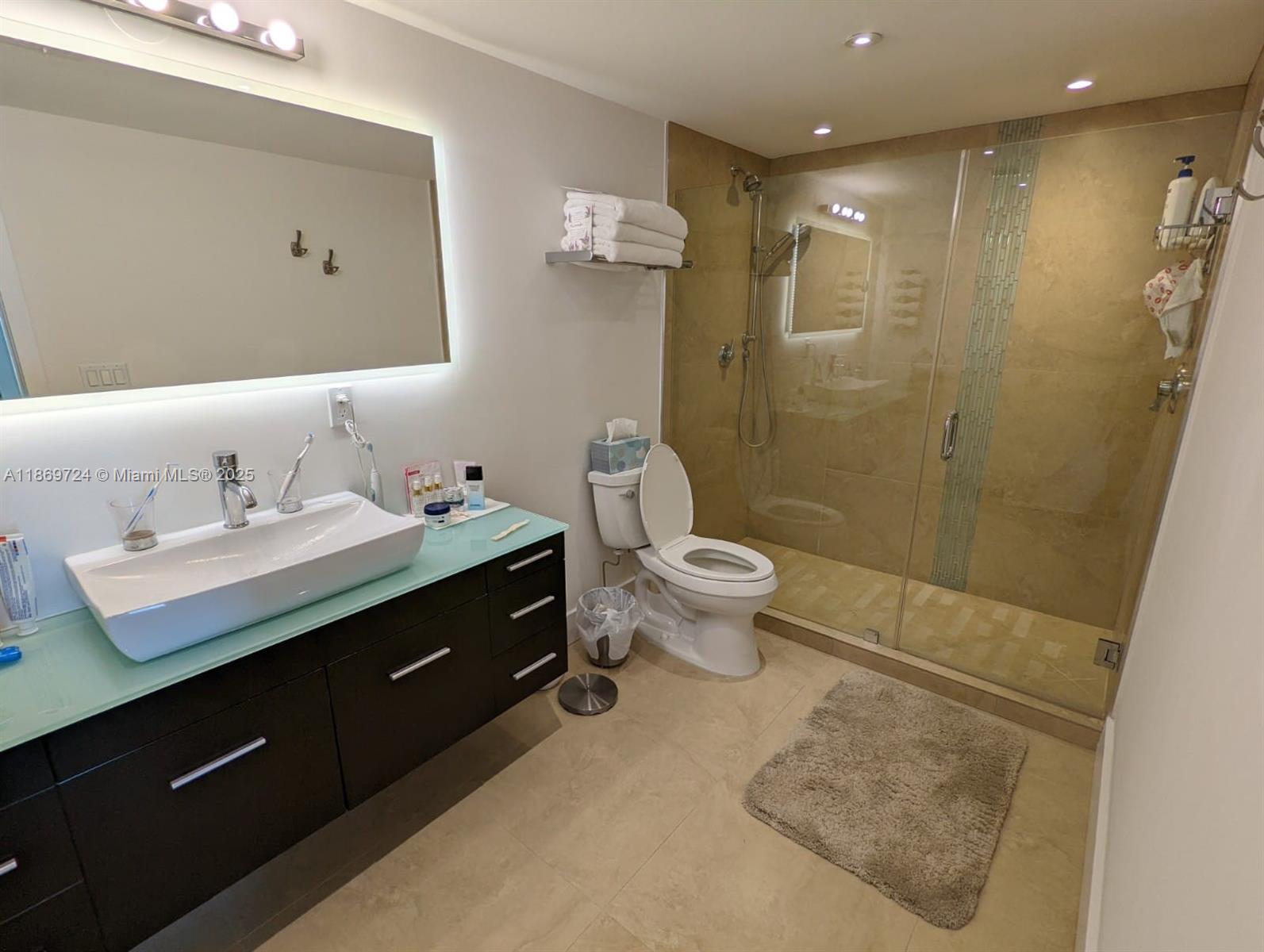 9273 Collins Avenue, Unit 1004 Surfside, FL 33154 - Photo 26 of 27 a bathroom with a sink toilet a mirror and shower