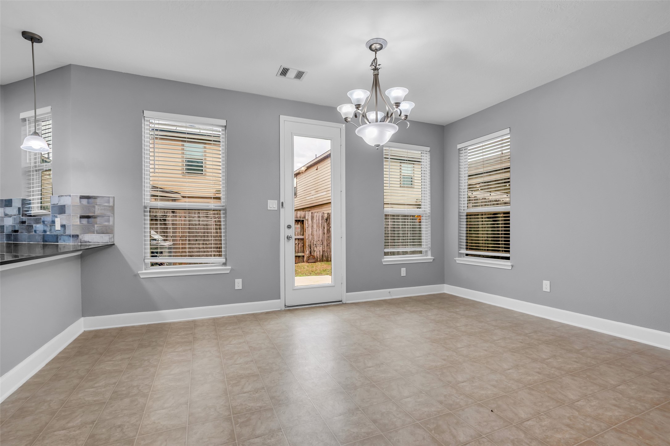2707 Volute Houston, TX 77038 - Photo 9 of 28 Above the spacious dining area hangs an elegant chandelier. The windows overlook the backyard, and a door provides direct access outside.