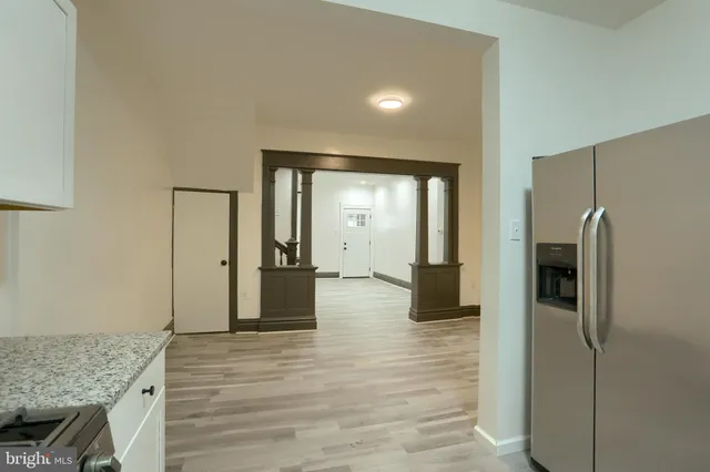 a view of a hallway with wooden floor and a living room