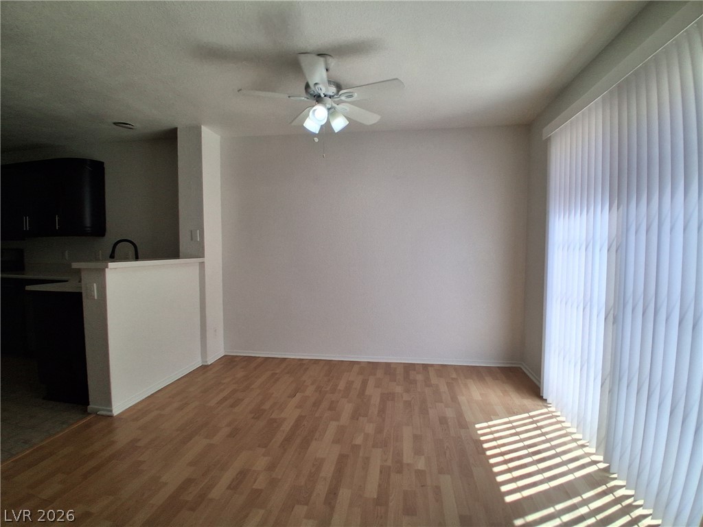 8023 Simone Avenue Las Vegas, NV 89147 - Photo 3 of 12 A living area features light wood flooring and a large window with vertical blinds, offering a clean, airy feel.