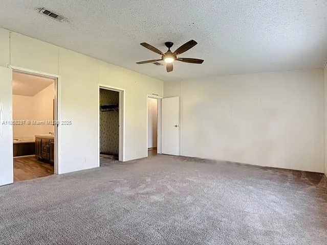 an empty room with closet and a ceiling fan