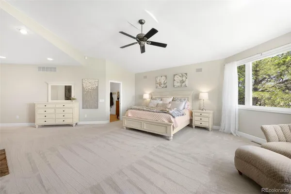a bedroom with a white bed and ceiling fan