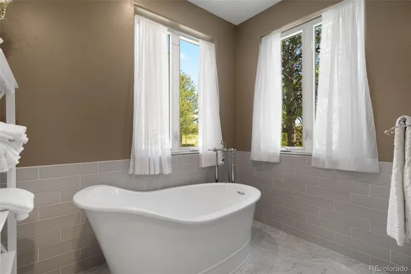 a white bath tub sitting in a bathroom next to a window