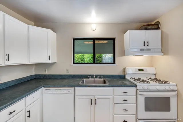 a kitchen with granite countertop white cabinets and white appliances