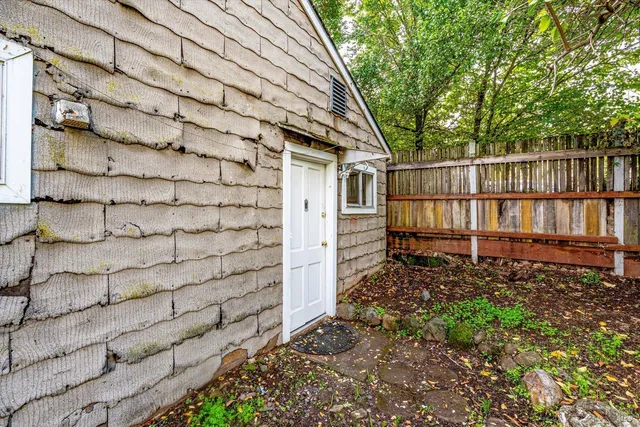 a view of a wooden house with a small yard and large tree