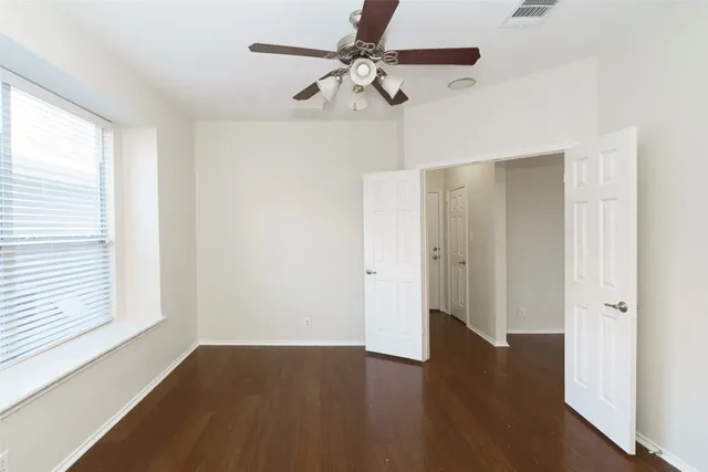 a view of an empty room with a window and wooden floor