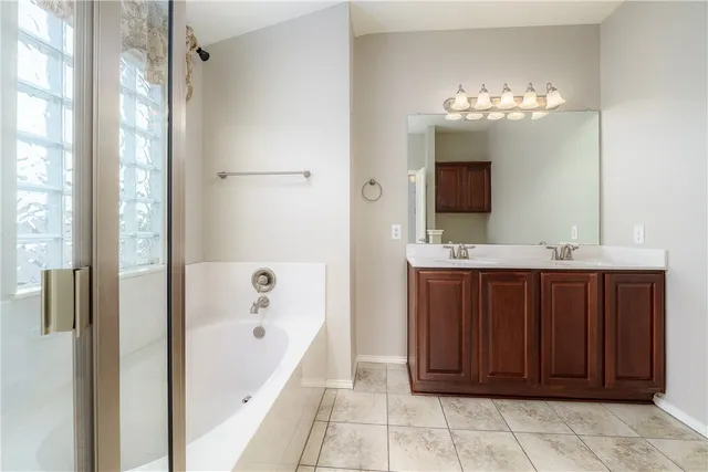 a bathroom with a tub a sink and a large mirror