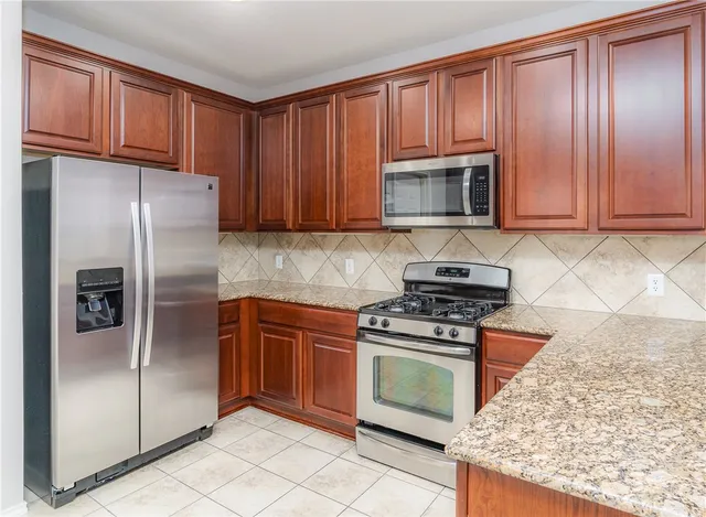 a kitchen with granite countertop wooden cabinets and stainless steel appliances