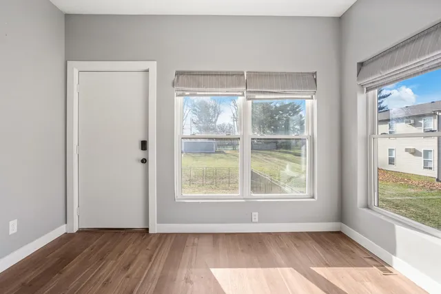 an empty room with wooden floor and windows