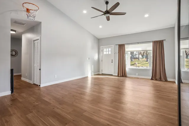 a view of an empty room with a window and wooden floor