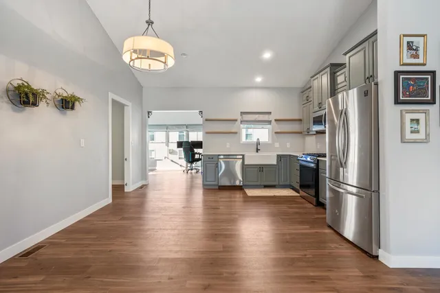 a kitchen with stainless steel appliances granite countertop a refrigerator a stove top oven a sink dishwasher and white cabinets with wooden floor