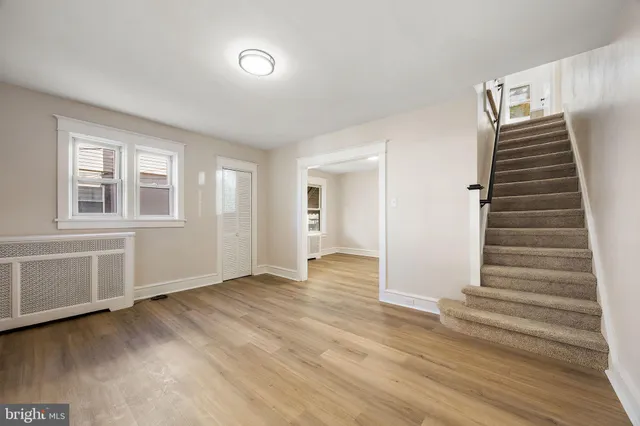 a view of an empty room with wooden floor and stairs