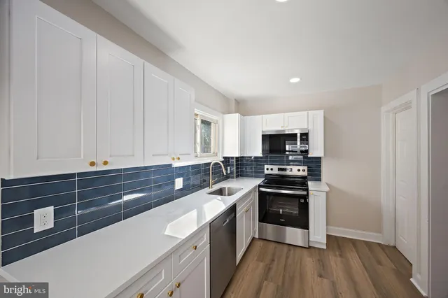 a kitchen with stainless steel appliances granite countertop a stove a sink and white cabinets