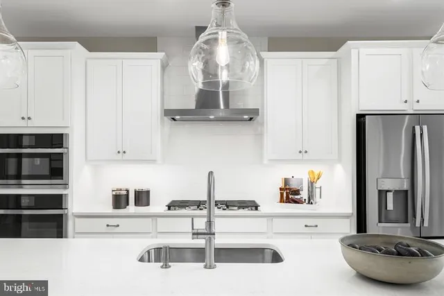 a kitchen with stainless steel appliances a sink a stove and white cabinets