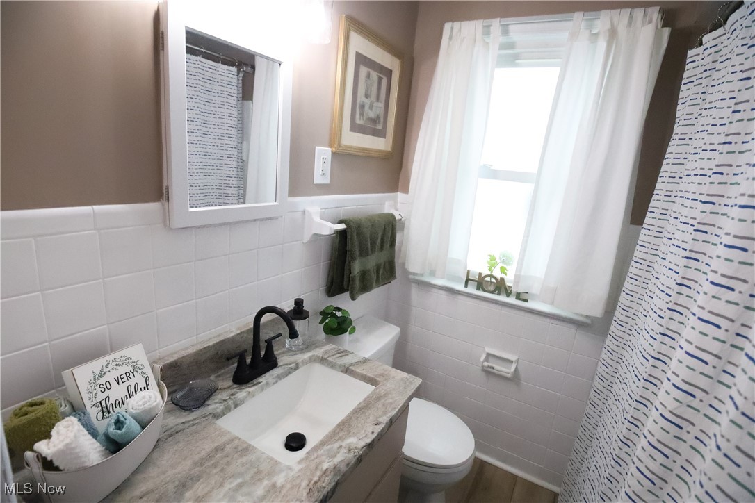 1344 Lander Road Cleveland, OH 44124 - Photo 27 of 49 Bathroom featuring curtained shower, vanity, tile walls, and wainscoting