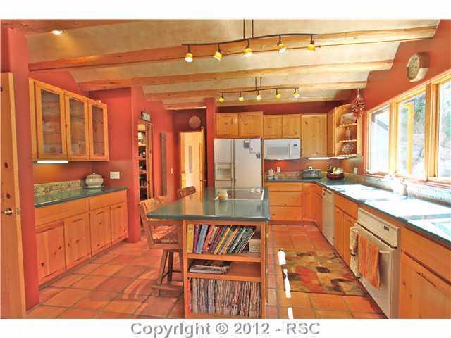 16 West Point Road Colorado Springs, CO 80906 - Photo 7 of 25 Kitchen is spacious with ample cabinetry, built in bookshelves island with smooth-top cooking surface and a gorgeous wall of windows overlooking the private backyard. Heated tile flooring