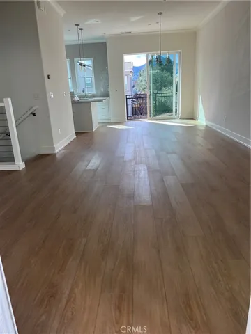a view of a room with wooden floor kitchen view and a window