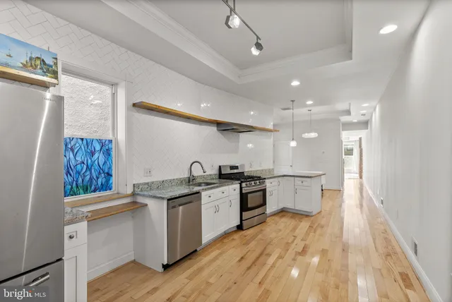 a large kitchen with a lot of counter space and wooden floor
