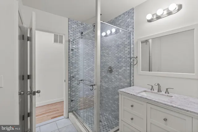 a bathroom with a granite countertop sink a mirror and shower