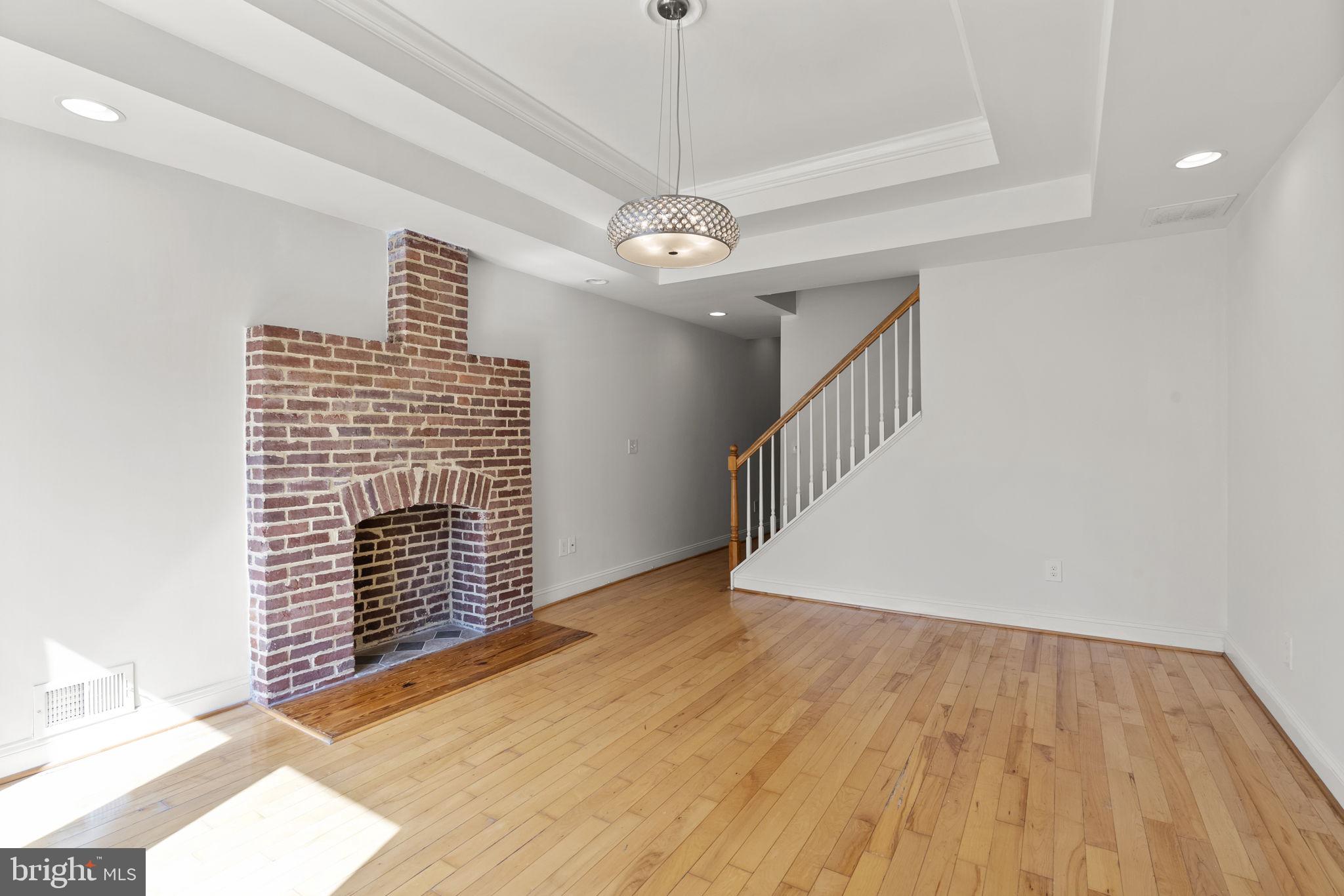 722 Lennox Street Baltimore, MD 21217 - Photo 5 of 52 a view of an empty room with wooden floor and a chandelier