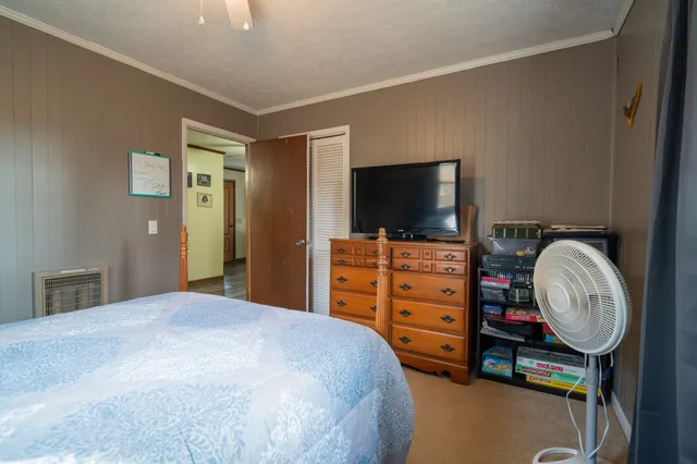 a bedroom with a bed dresser and a flat tv screen
