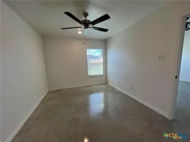 an empty room with a window and a fan