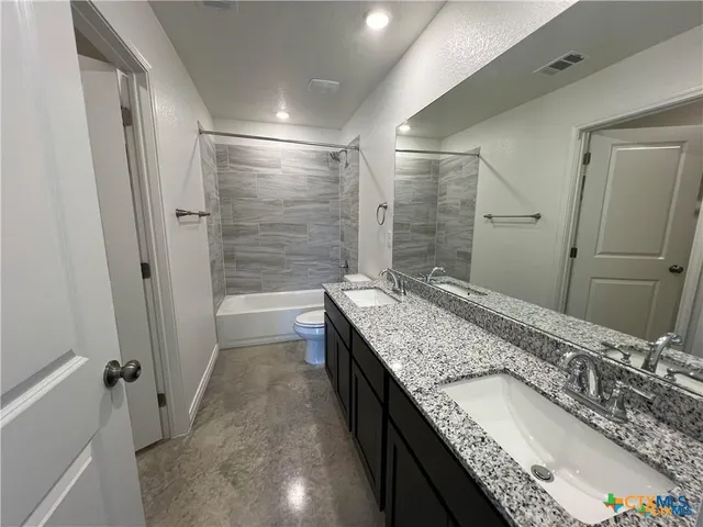 a bathroom with a granite countertop sink a mirror and shower