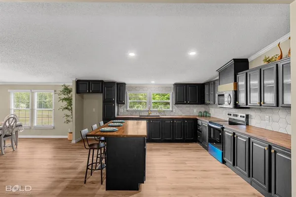 a kitchen with stainless steel appliances granite countertop a refrigerator a stove a sink a dining table and chairs