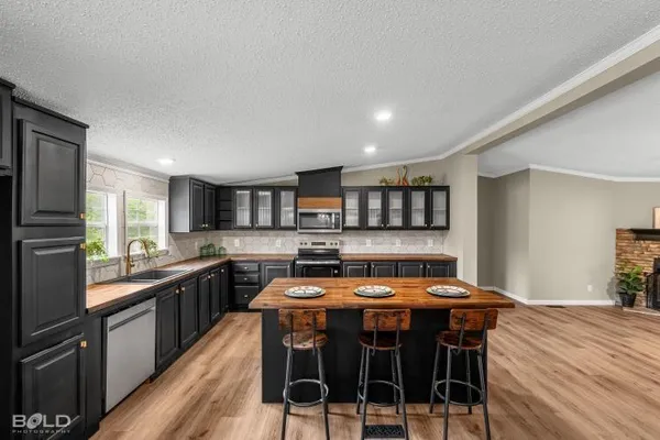 a large dining hall with stainless steel appliances granite countertop a stove and a wooden floors