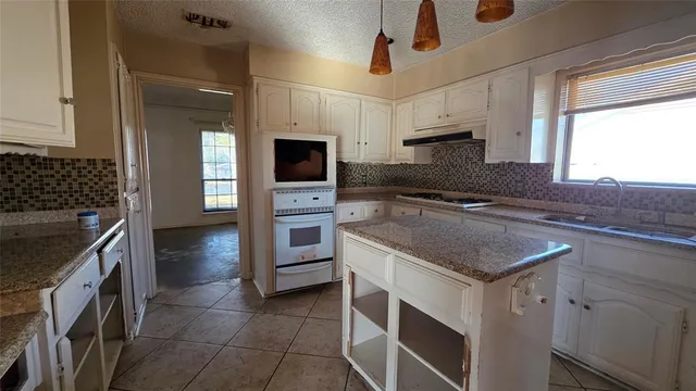 a kitchen with stainless steel appliances granite countertop a stove a sink and a microwave