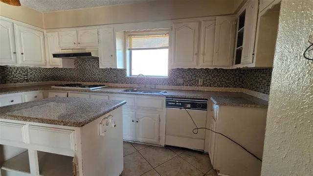a kitchen with granite countertop a sink stove and cabinets