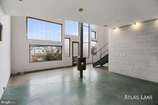 a view of an empty room with stairs and wooden floor