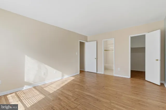 a view of an empty room with wooden floor and closet