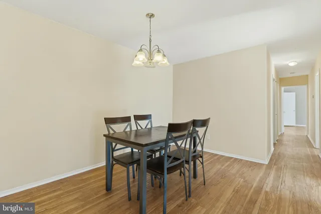 a view of a dining room with wooden floor a chandelier a wooden table and chairs
