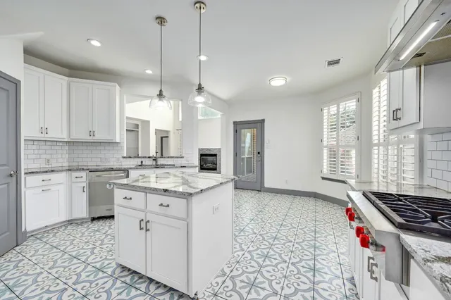 a kitchen with stainless steel appliances granite countertop a sink a stove a refrigerator and white cabinets