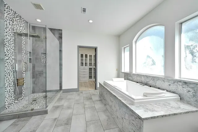 a bathroom with a granite countertop tub sink shower and mirror