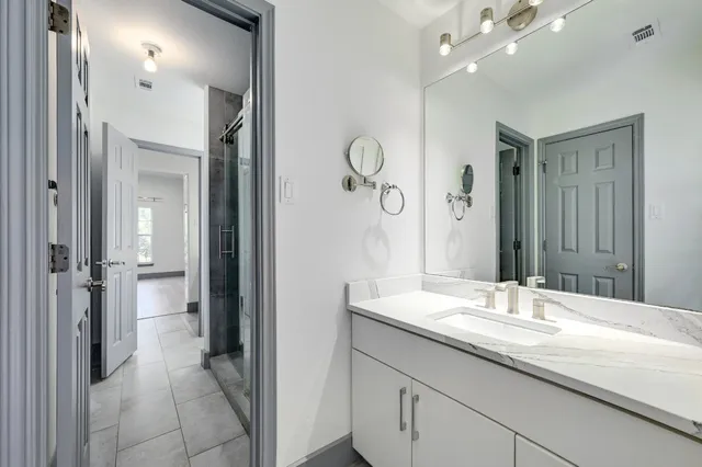a bathroom with a granite countertop sink a mirror and a shower